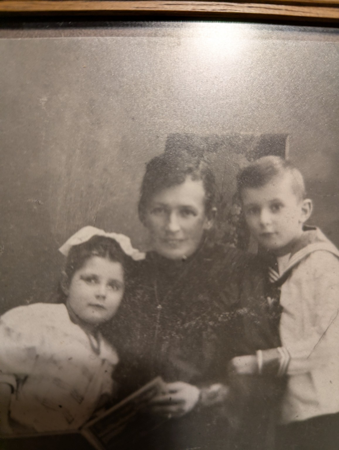 Das Foto zeigt eine Frau mit einem Kind im Vorschulalter und einem Kind im Grundschulalter, retro und monochrom, unrestauriertes Foto,  Anfang des 20 Jahrhunderts